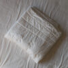 Gefaltete Merino-Bettdecke mit Steppung auf einem Bett