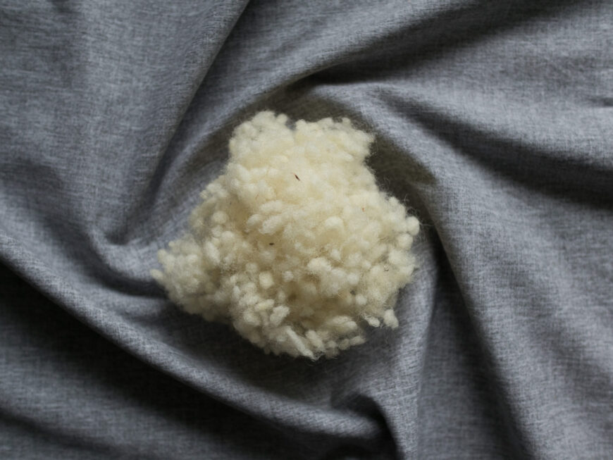 Schafswollefüllung für Körnerkopfkissen auf grauem Hintergrund.