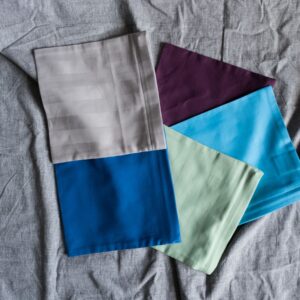 Kissenkorner Wärmekissen-Bezüge in mehreren Unifarben gefächert: Grau gestreift, Aubergine, Hellblau, Mint und Blau
